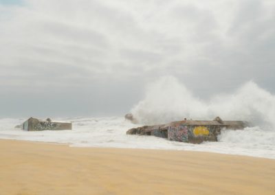 a large wave crashes over a building on the beach